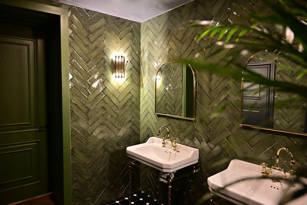 A chic restroom with elegant fixtures and green tiling