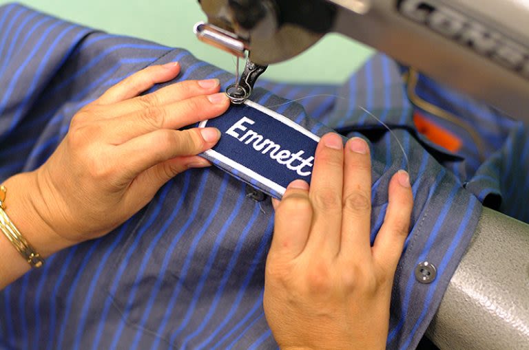 Alsco employee sewing on a patch to our uniform