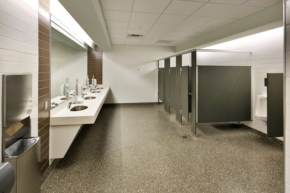 An office men's restroom with urinals, stalls, and sinks