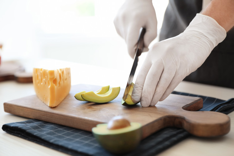Person wearing HPPE cut-resistant gloves cutting an avocado with a knife.
