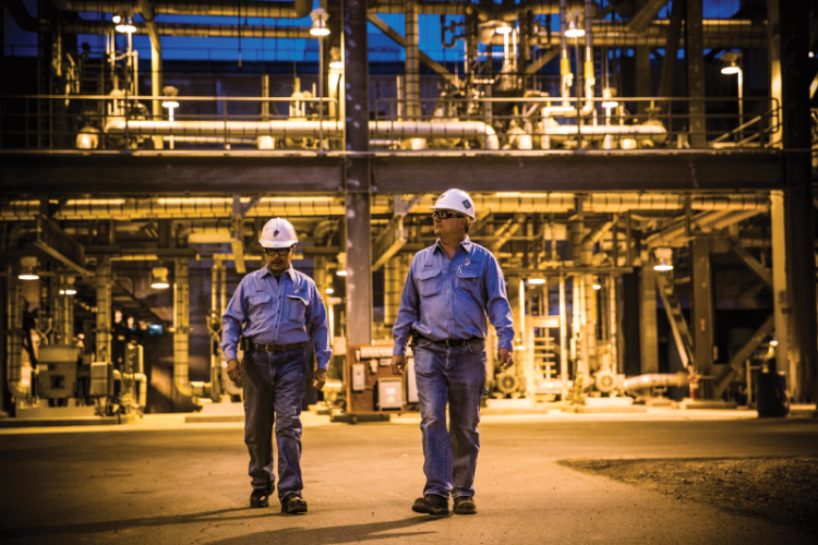Two uniformed men working in a refinery.