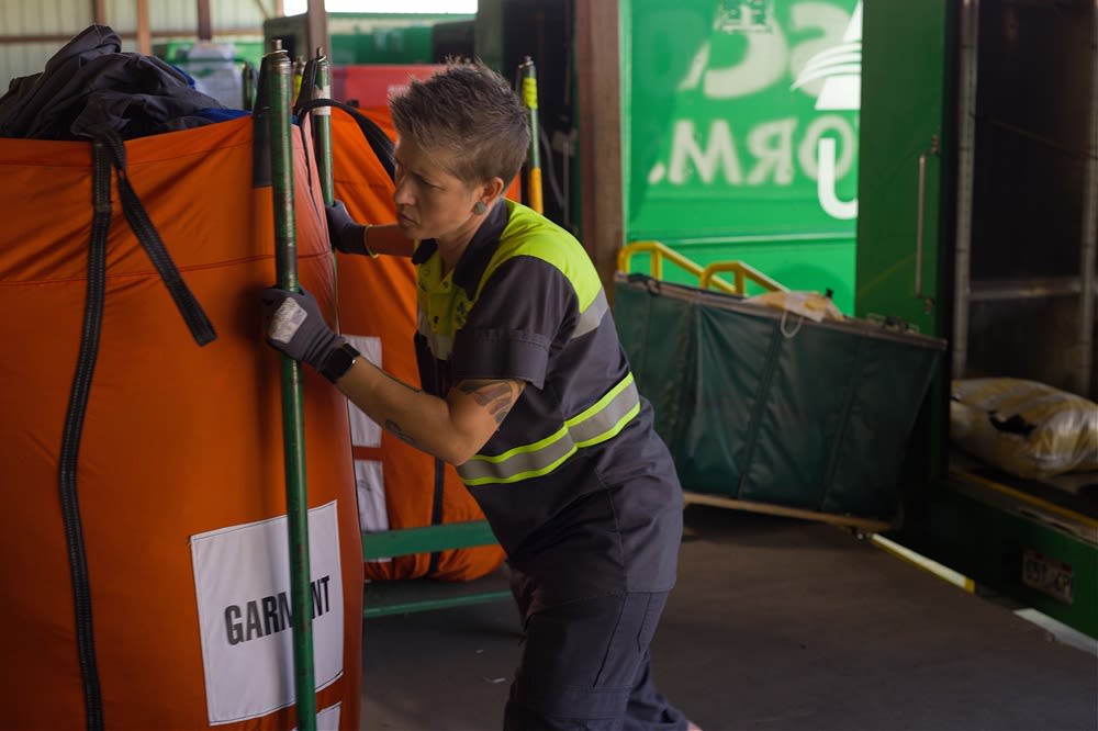 An Alsco Uniforms RSR unloading laundry from a truck.