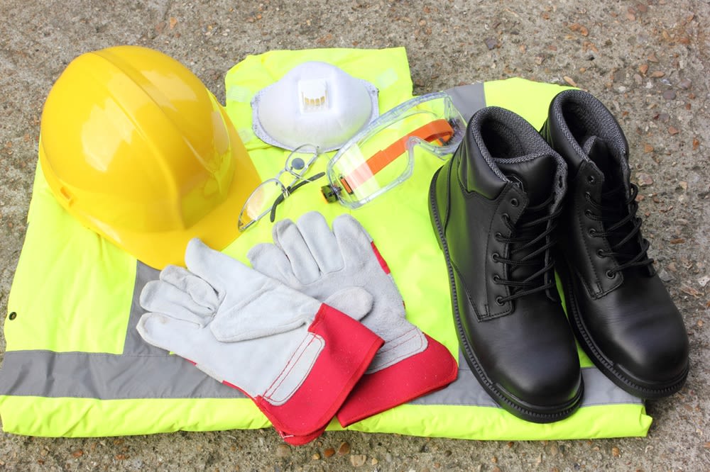 Collection of personal protective equipment including hard hat, goggles, mask, boots, and gloves.