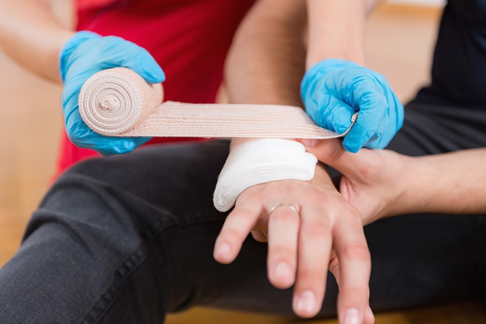 Someone wrapping a wrist injury with gauze.