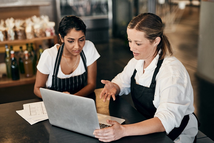Two restaurant employees looking at papers and a laptop