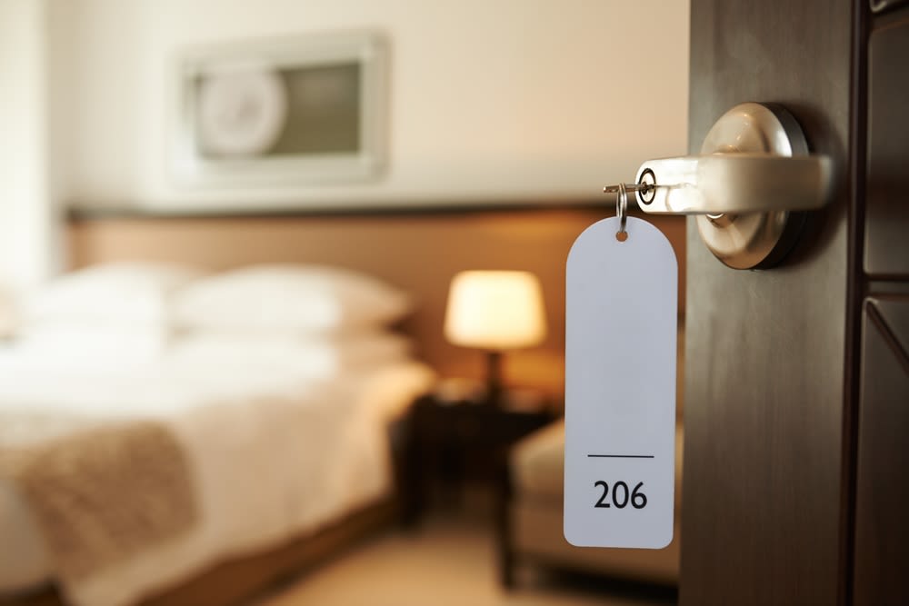 An open door leading into a hotel room. The hotel room number, 206, is hanging from a key in the door.