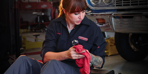 Woman wearing dirty automotive uniform.