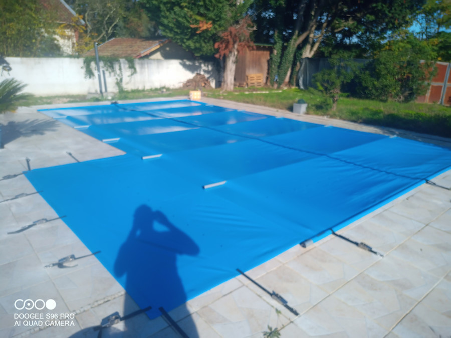 Bâche de sécurité piscine bleue installée sur bassin extérieur