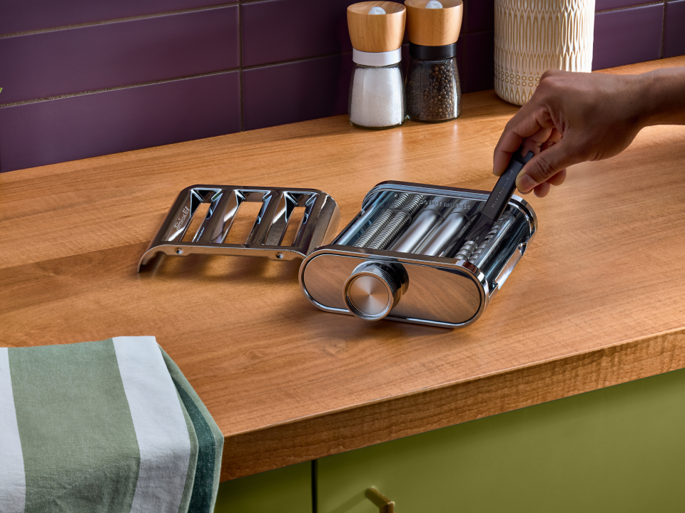 A person cleaning the 3-in-1 metal pasta attachment. 