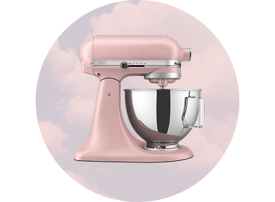 A Matte Dried Rose stand mixer on a pale pink background with clouds.