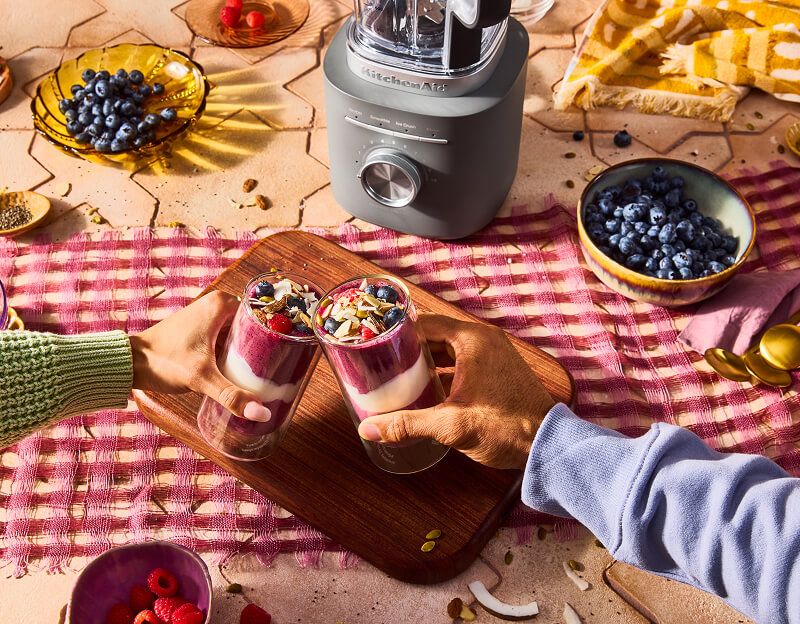 Two people with smoothies, in front of a KitchenAid® blender.