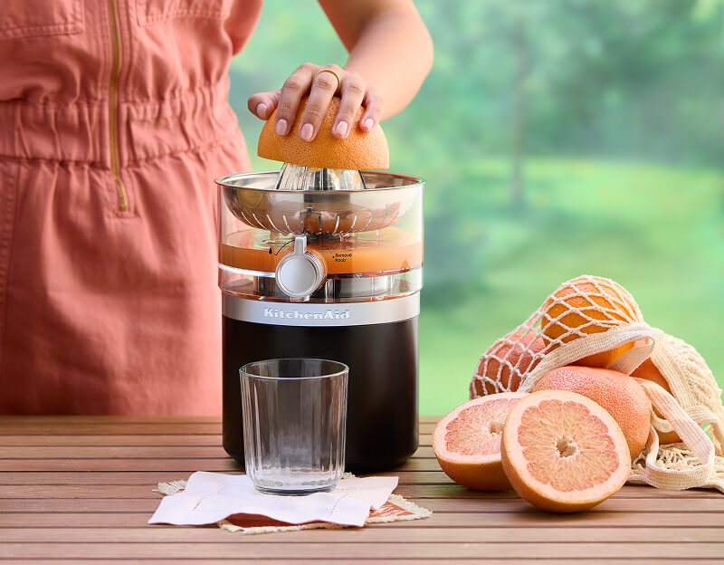 A person juicing a grapefruit using a KitchenAid® Juicer.