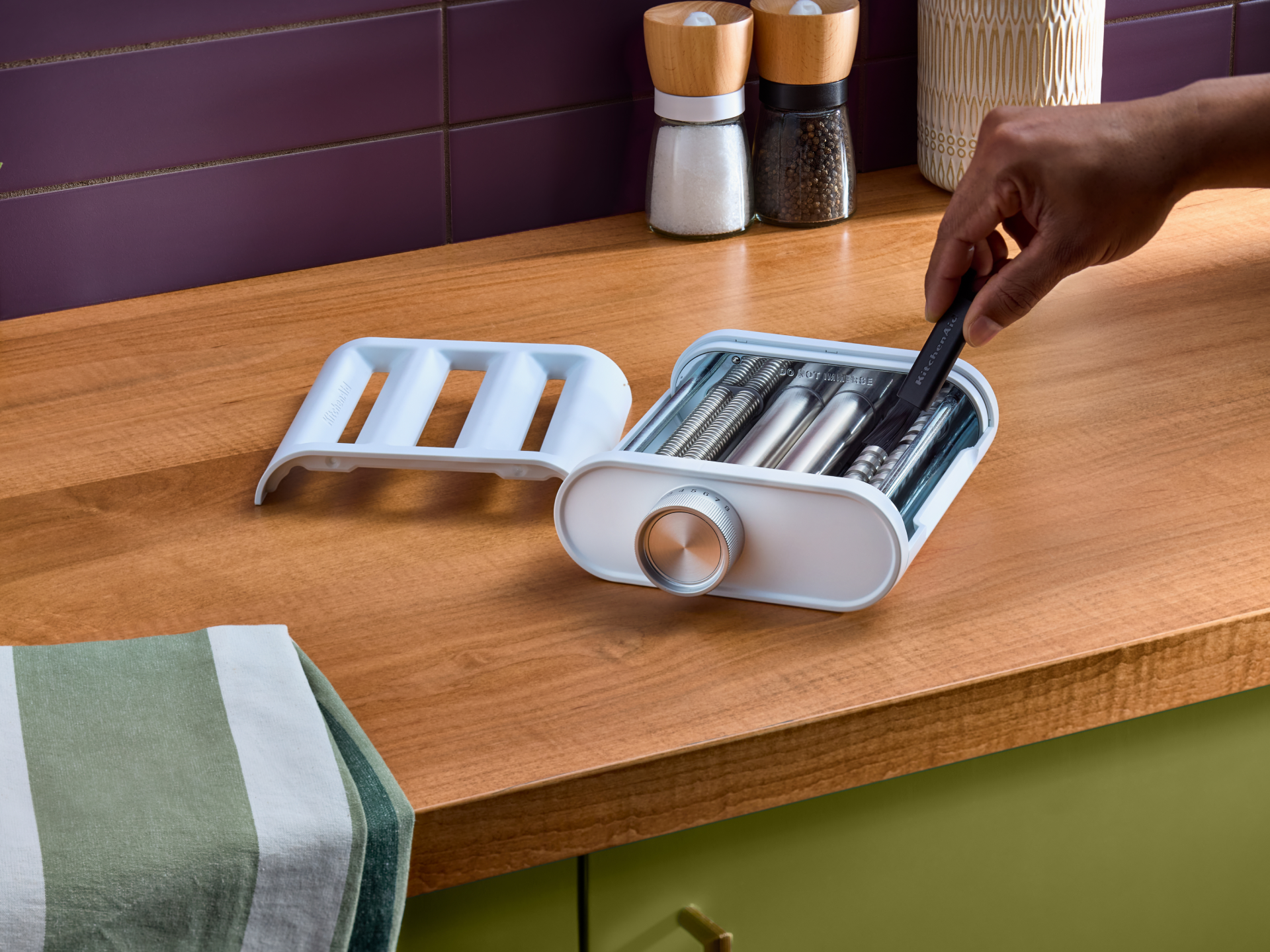 A person cleaning the 3-in-1 pasta attachment. 