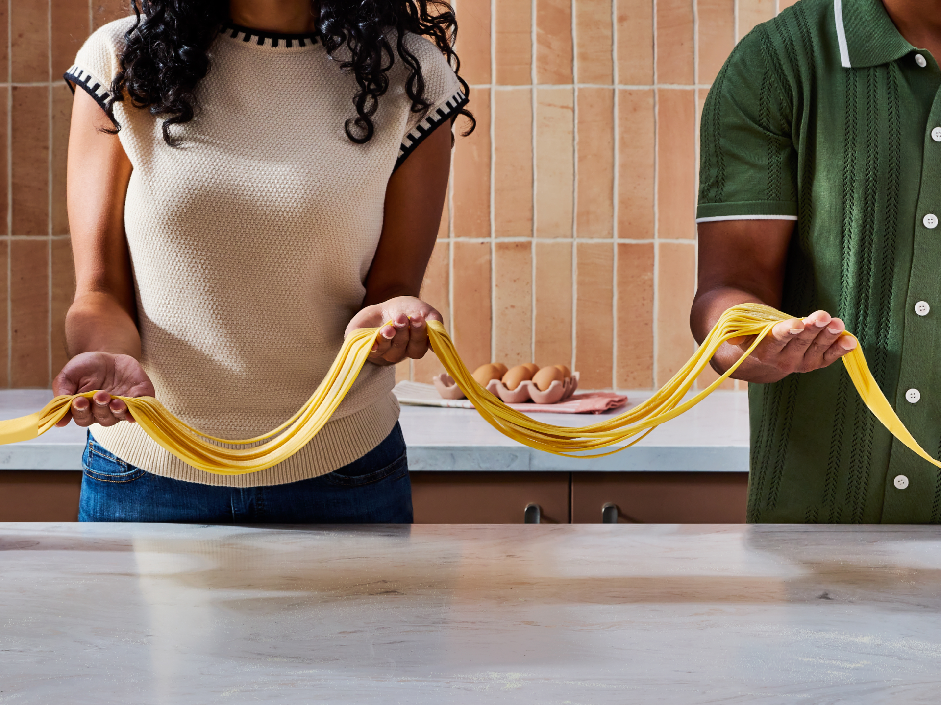 People rolling dough into pasta with the 3-in-1 pasta attachment. 