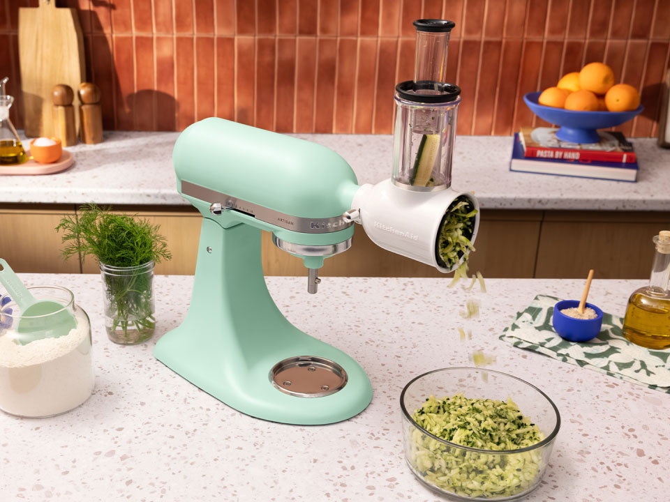 A Spearmint stand mixer on a countertop with a shredding attachment.