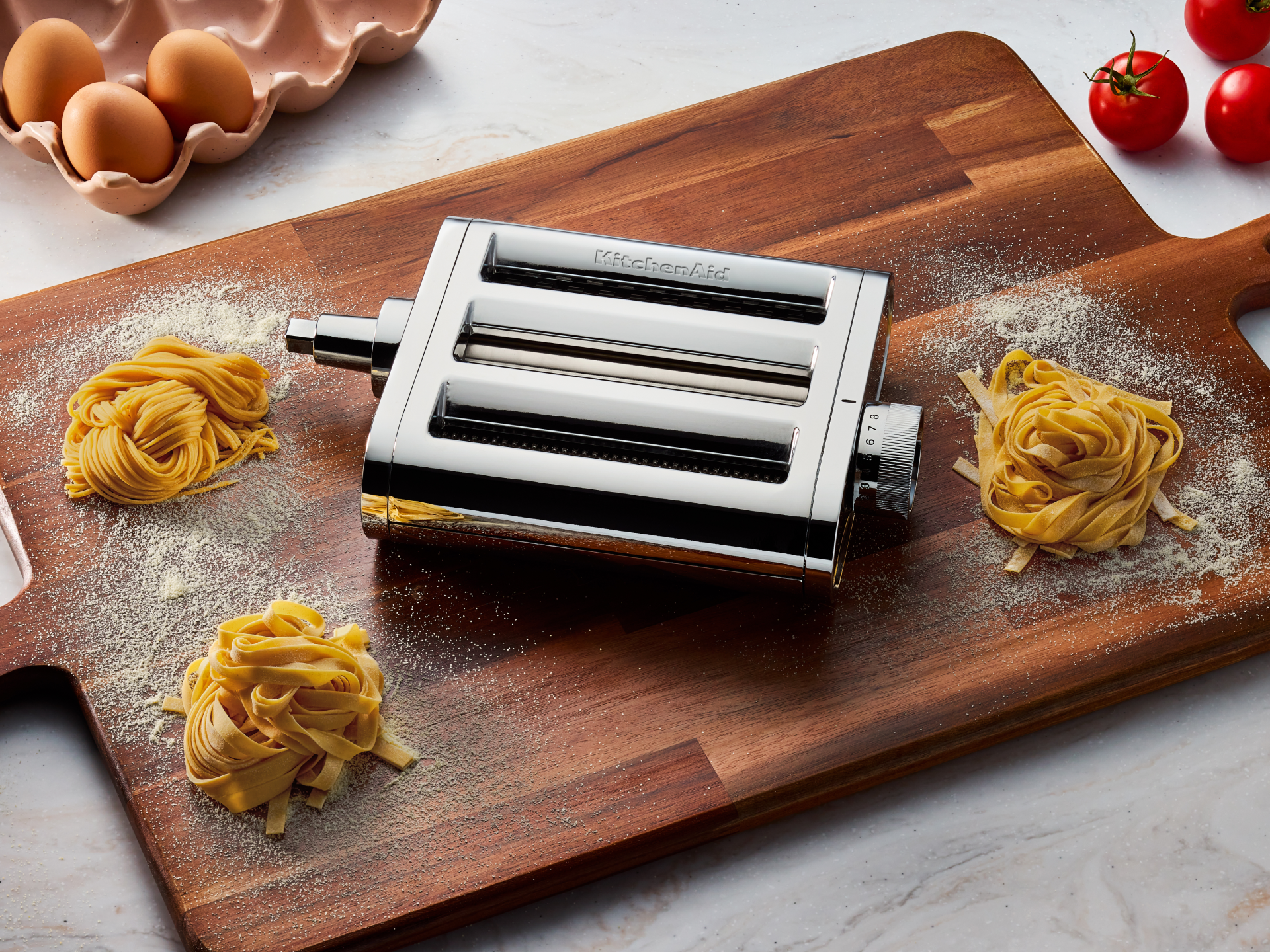 The 3-in-1 metal pasta attachment on a cutting board. 