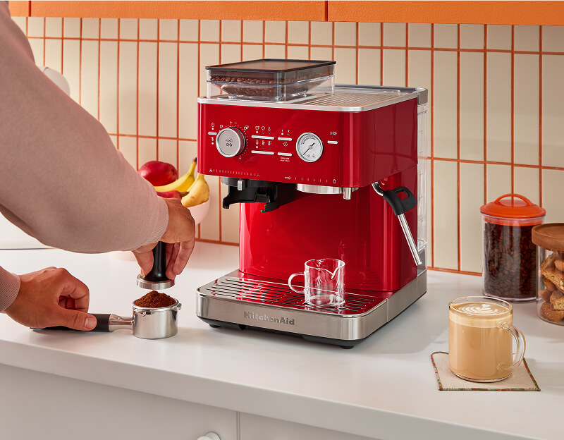 A person making espresso with a KitchenAid® semi-automatic espresso machine