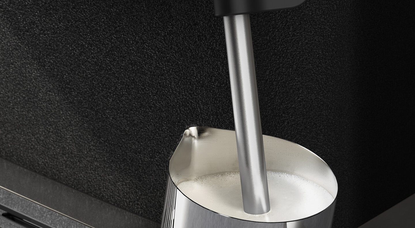 Espresso machine steam wand inside a milk carafe