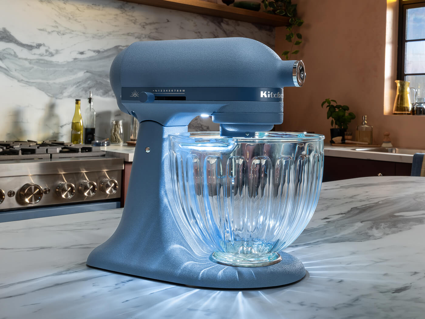 KitchenAid® Luminaire stand mixer with a glass bowl on a marble counter