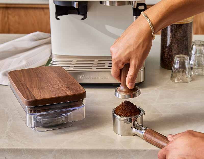 A person tamping espresso grounds into the portafilter.