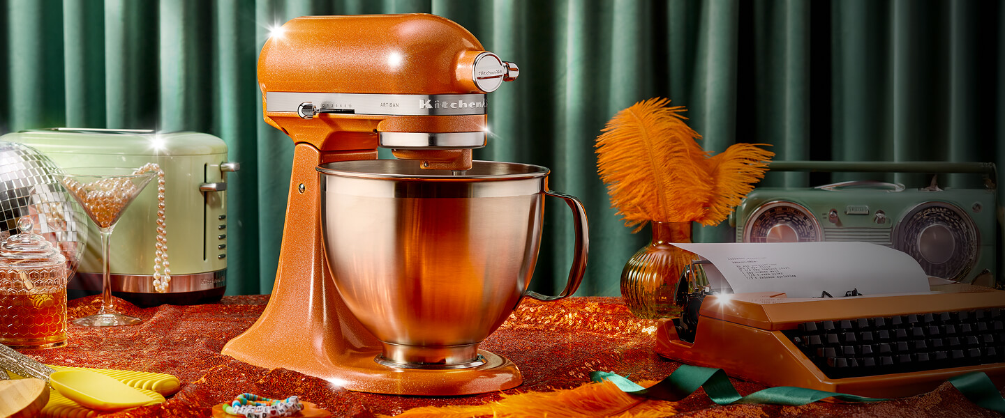 A Tangerine Twinkle stand mixer on a teal blue background with cat, stand mixer and accessory "stickers" on it.