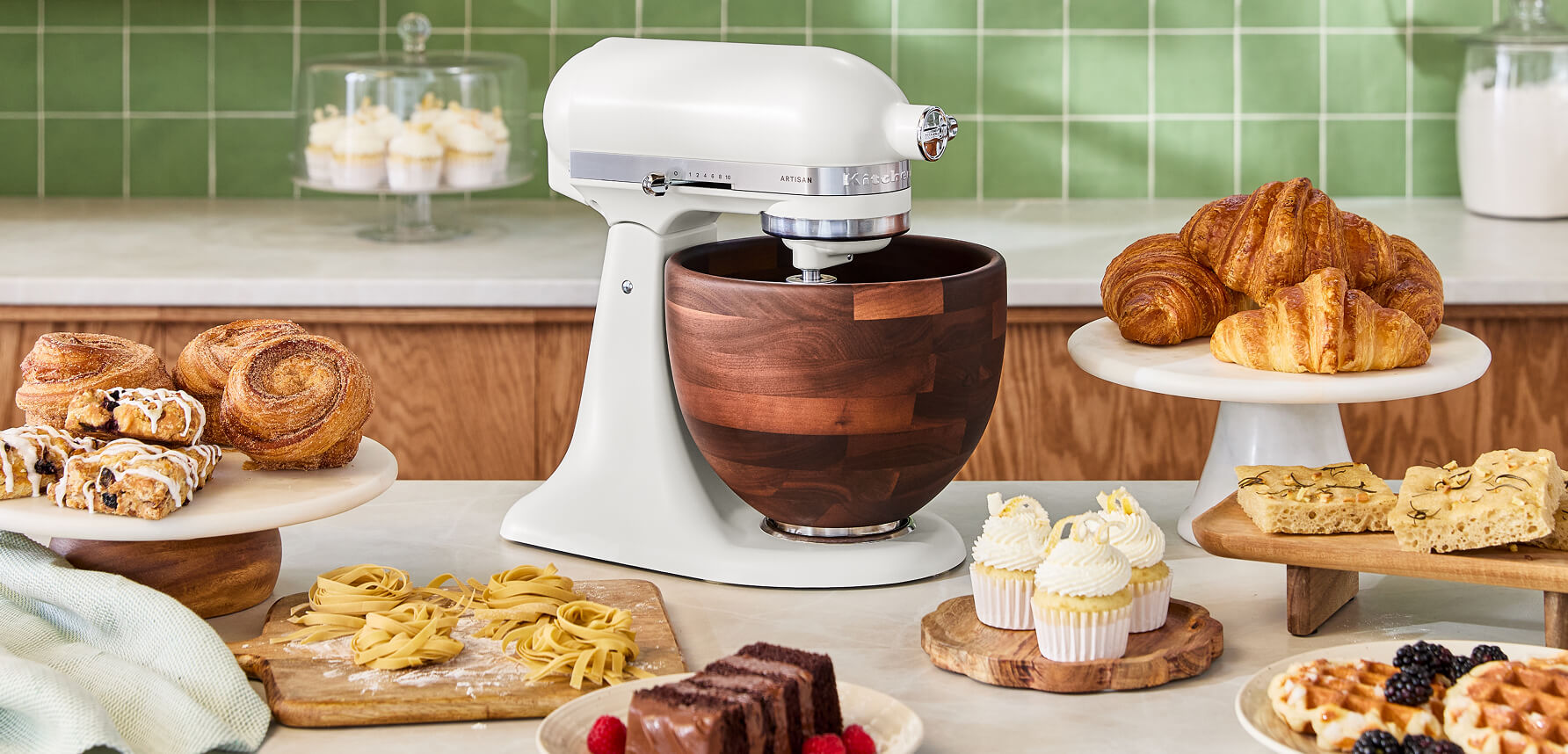 A KitchenAid® Stand Mixer in Porcelain White, surrounded by pastries