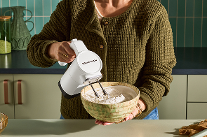 A person using a hand mixer.
