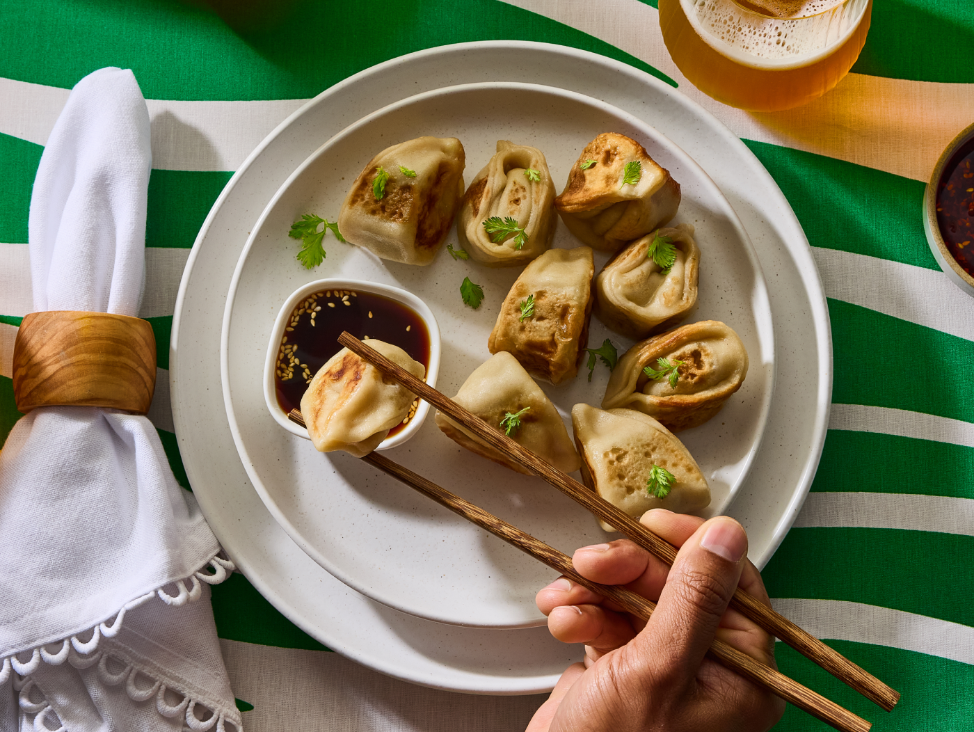 A person dipping a dumpling with chopsticks.