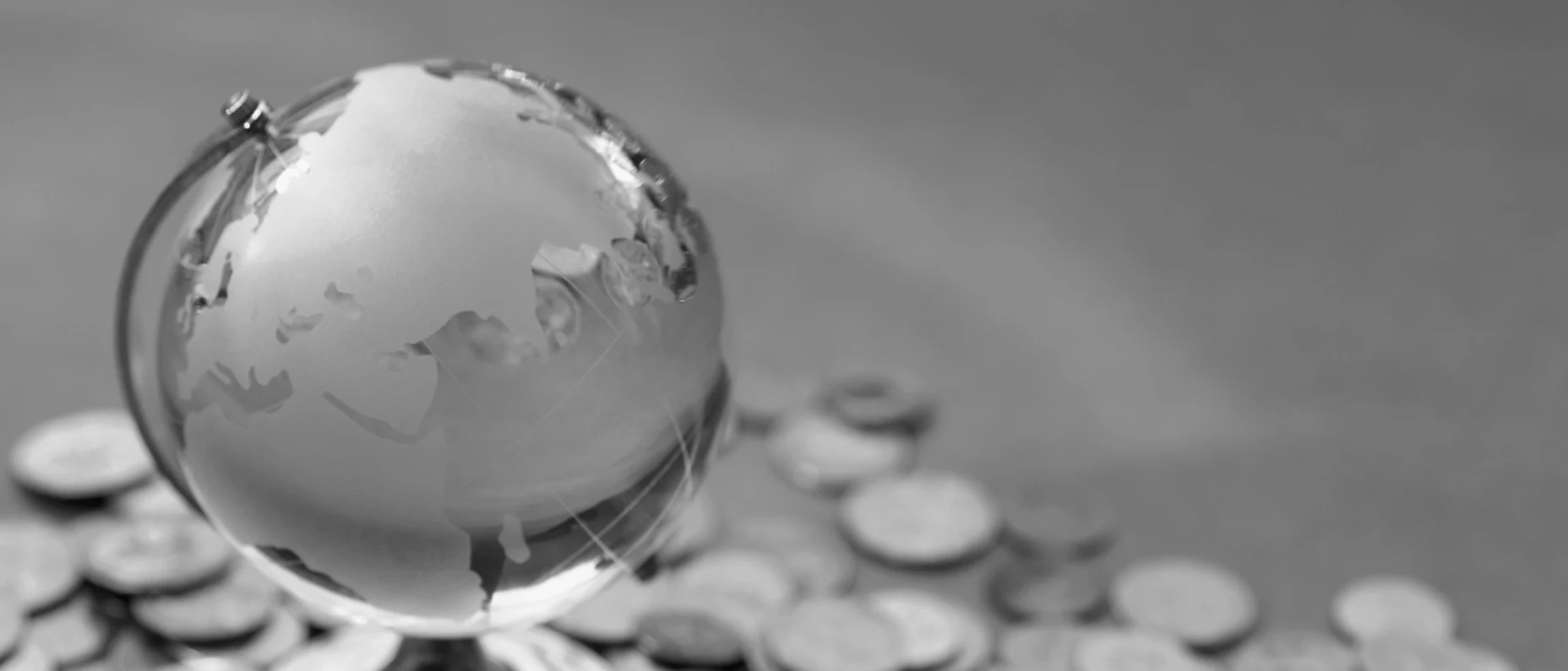 kleine Weltkugel mit herumliegenden Geldmünzen
