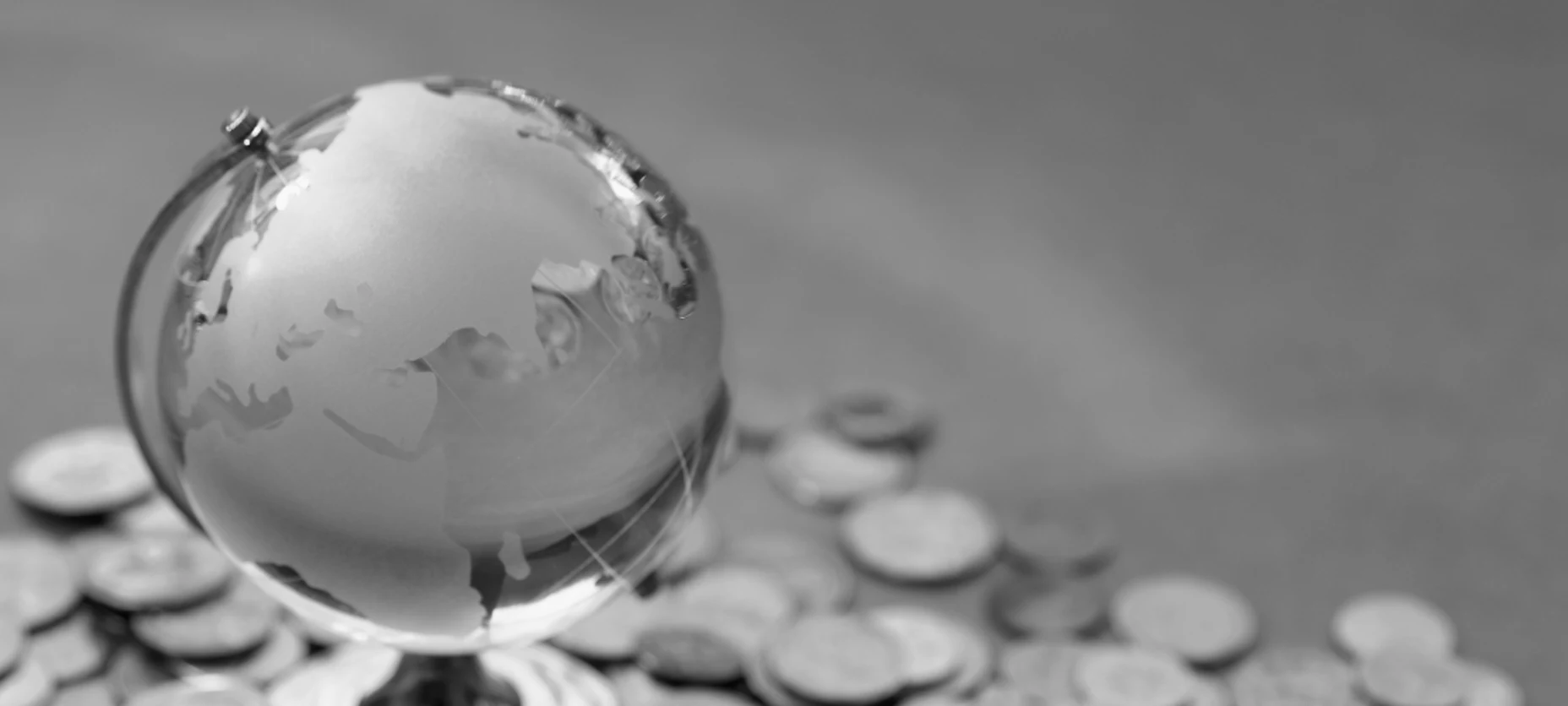 kleine Weltkugel mit herumliegenden Geldmünzen
