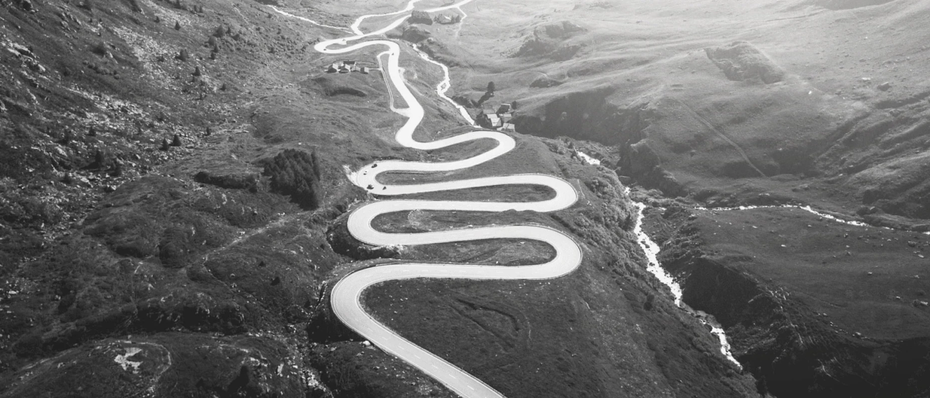 Schwarz-Weiß-Bild einer Straße in den Bergen mit einigen Serpentinen.