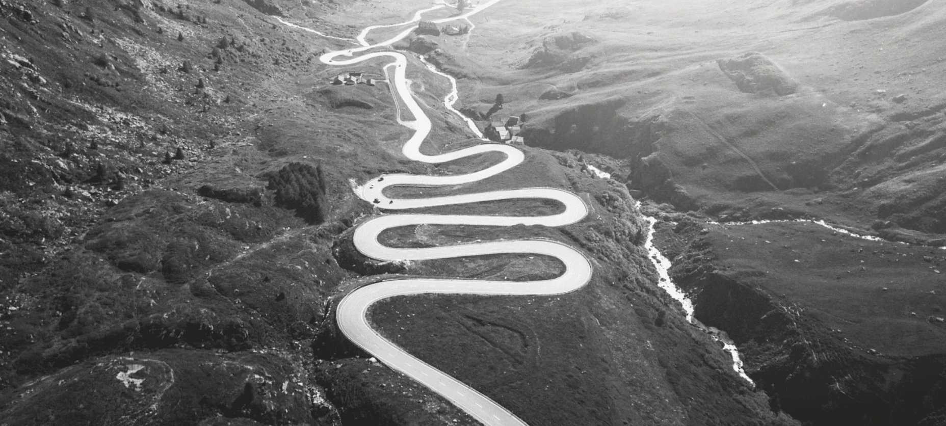 Schwarz-Weiß-Bild einer Straße in den Bergen mit einigen Serpentinen.