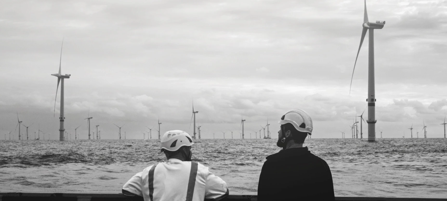 zwei Arbeiter schauen auf Windpark im Wasser 