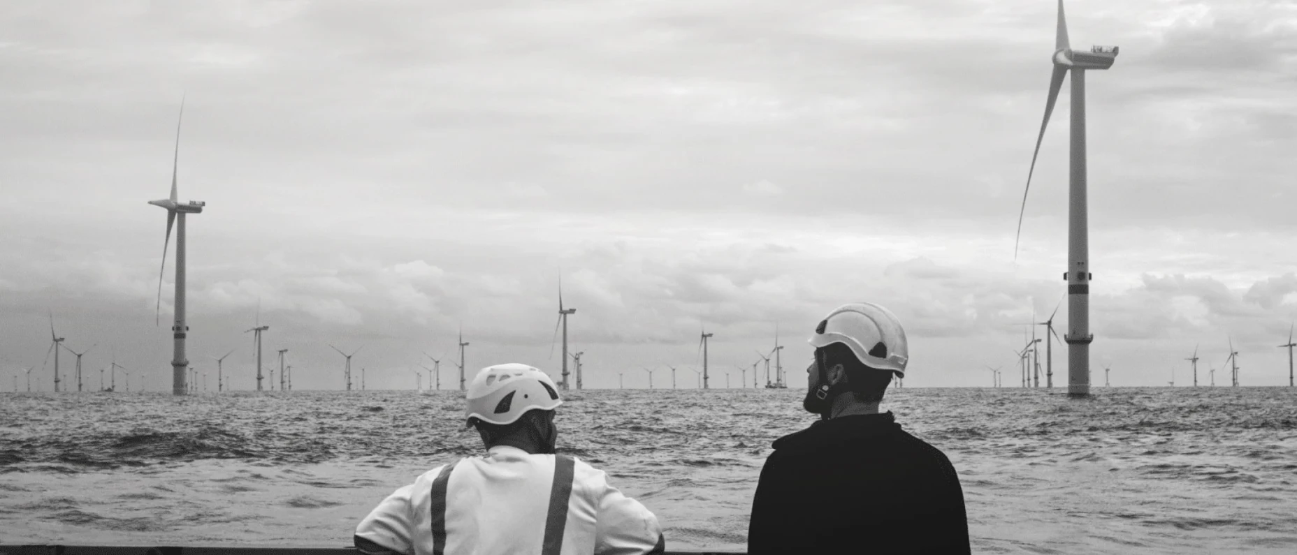 zwei Arbeiter schauen auf Windpark im Wasser 