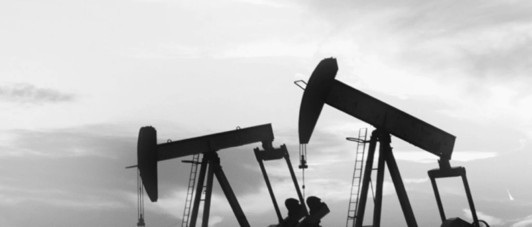 Schwarz-Weiß-Bild von zwei Ölbohrern auf einem Feld.