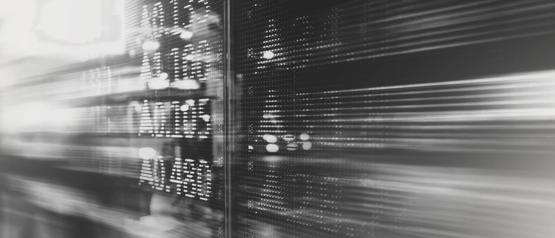Schwarz-Weiß-Bild einer verschwommenen Börsentafel.
