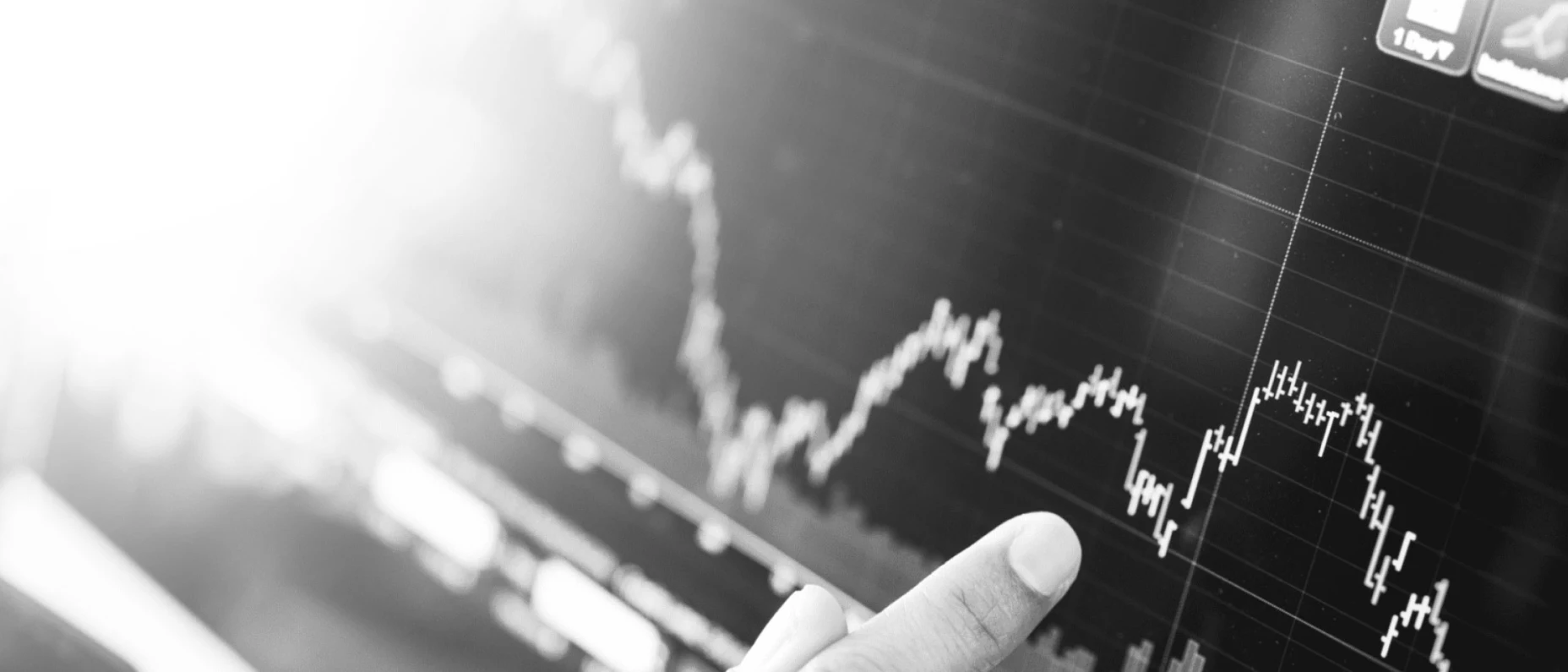 Schwarz-Weiß-Bild eines Kursverlaufs und ein Finger der darauf zeigt.
