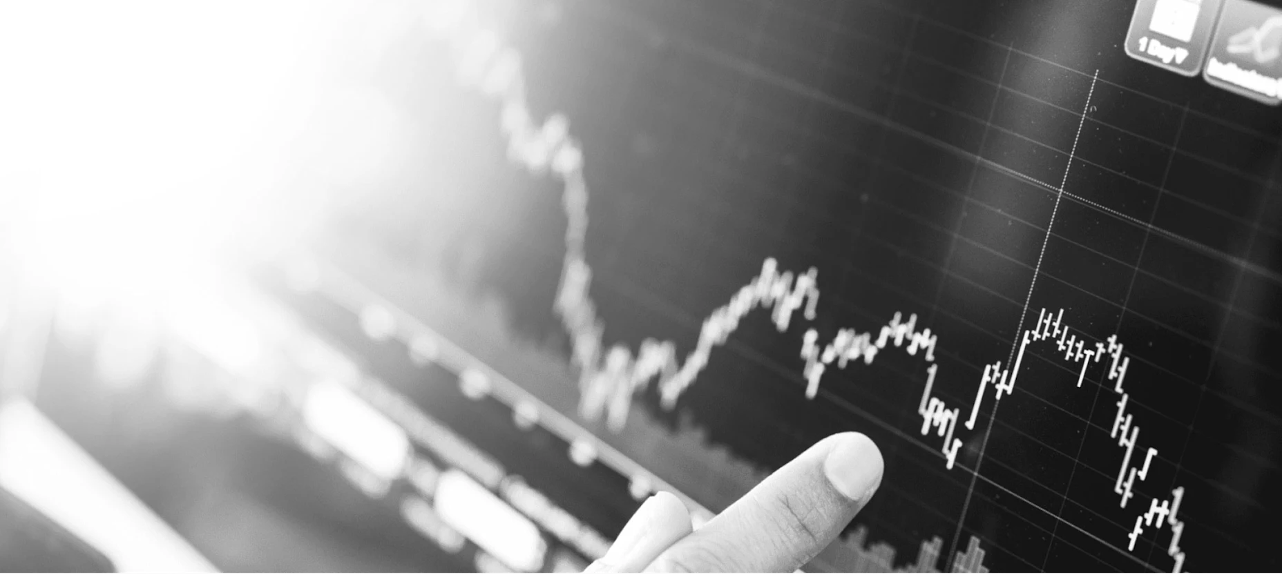 Schwarz-Weiß-Bild eines Kursverlaufs und ein Finger der darauf zeigt.