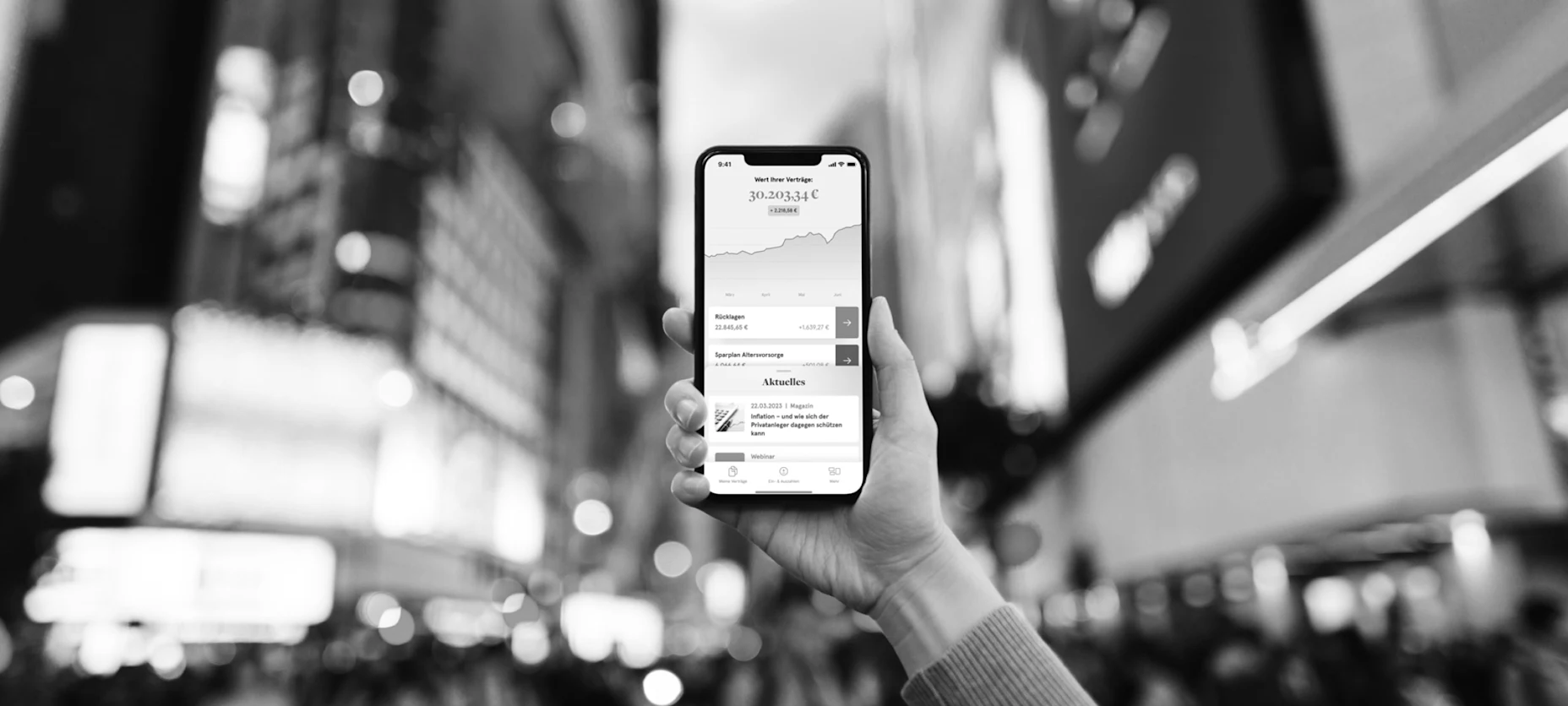 Schwarz-Weiß-Bild eines Handys mit geöffneter Allvest App und der Stadt im Hintergrund.