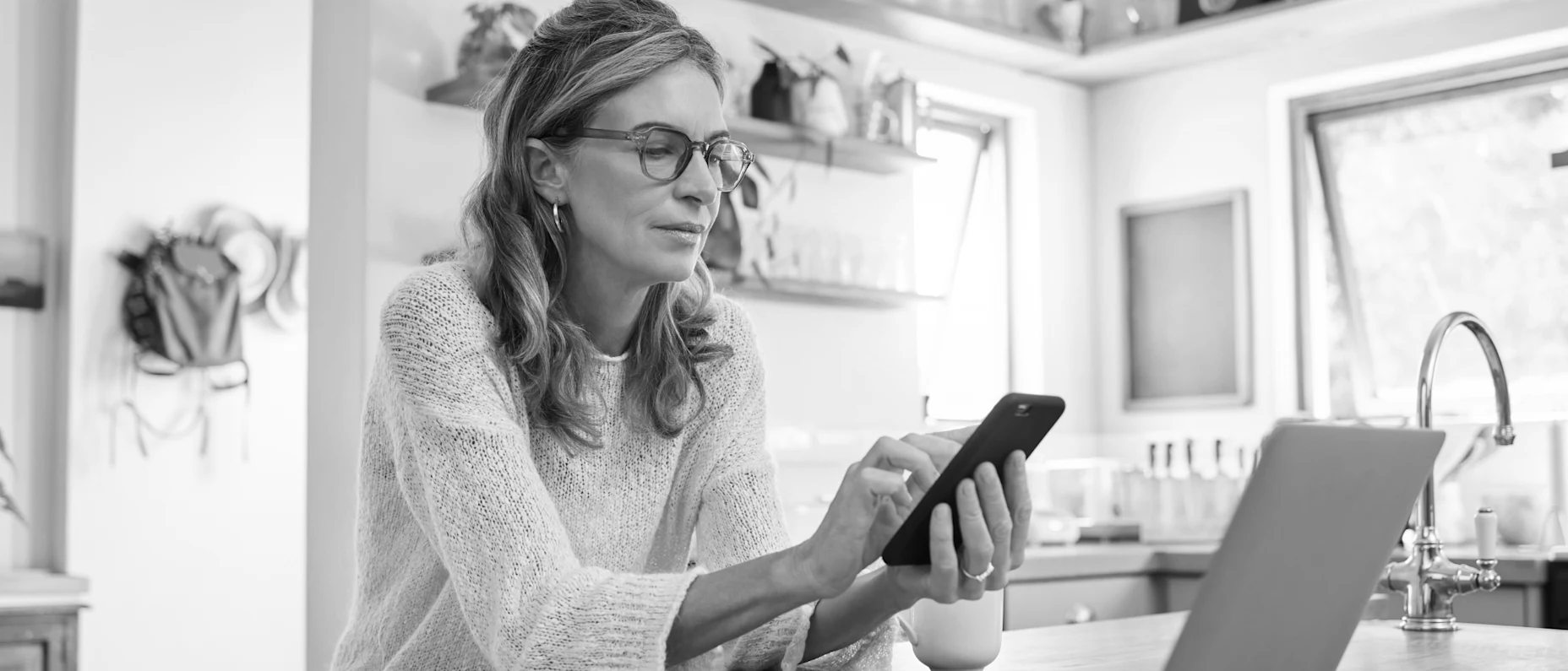 Frau, die an einem Tisch sitzt und auf ihr Handy schaut und es bedient