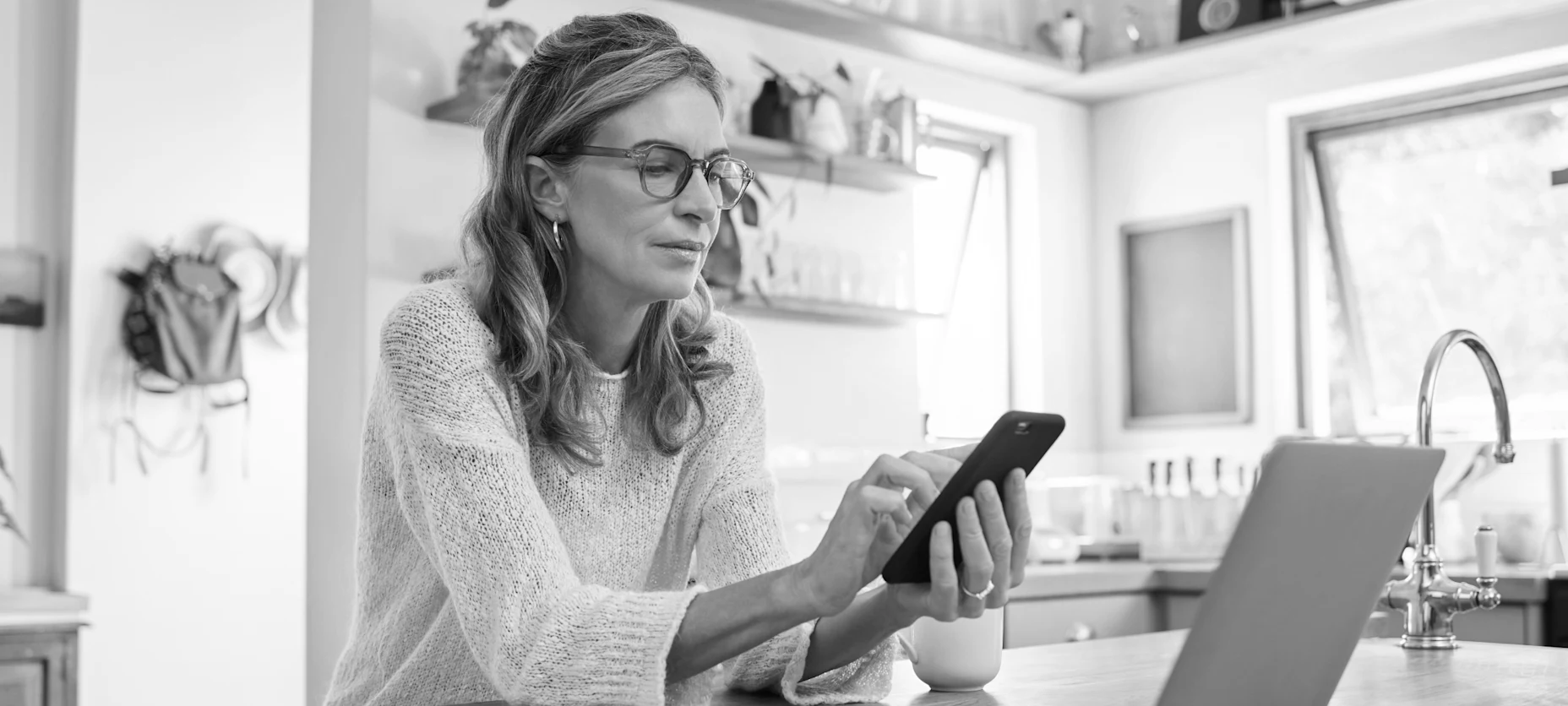 Frau, die an einem Tisch sitzt und auf ihr Handy schaut und es bedient