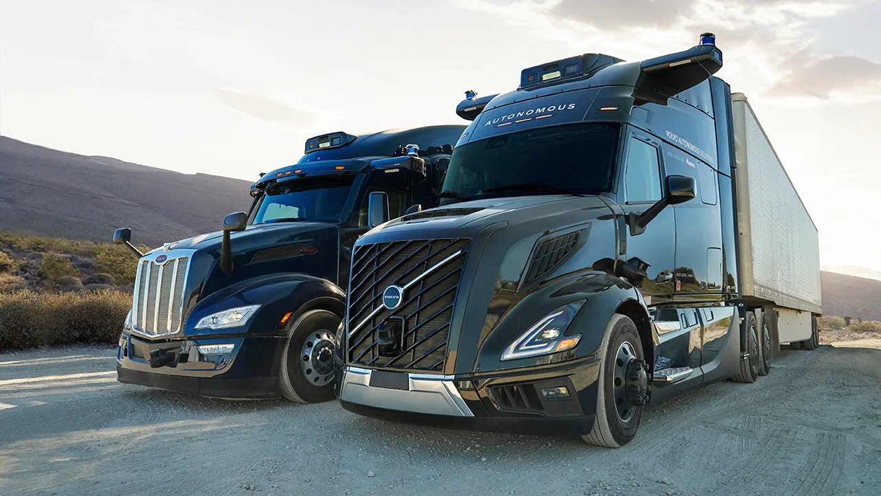 Two Aurora trucks parked in a desert landscape