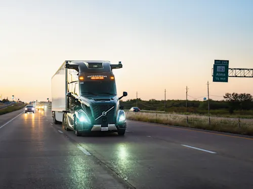 Aurora self-driving truck driving down highway with sunset in the background