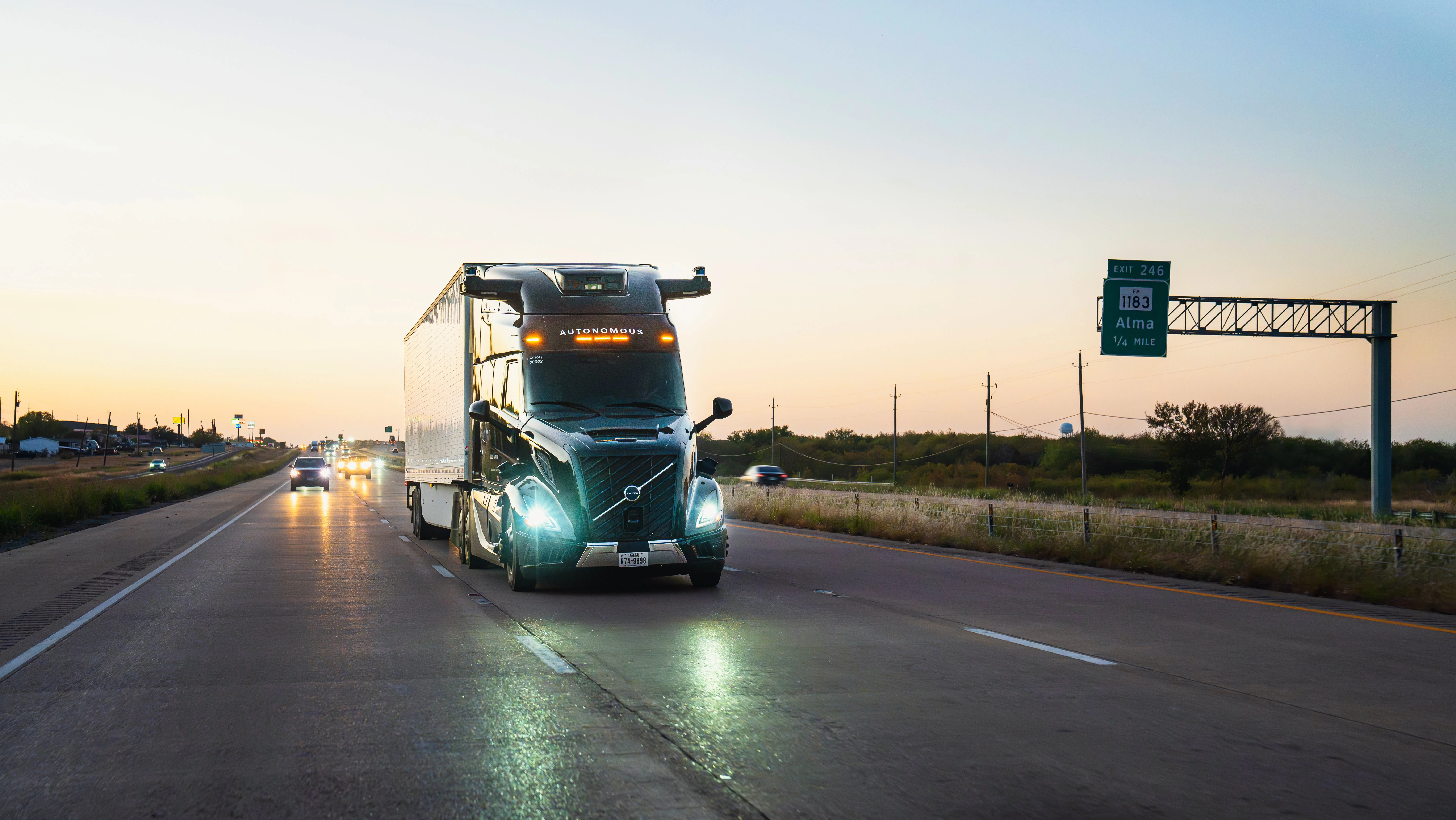 Aurora self-driving truck driving down highway with sunset in the background