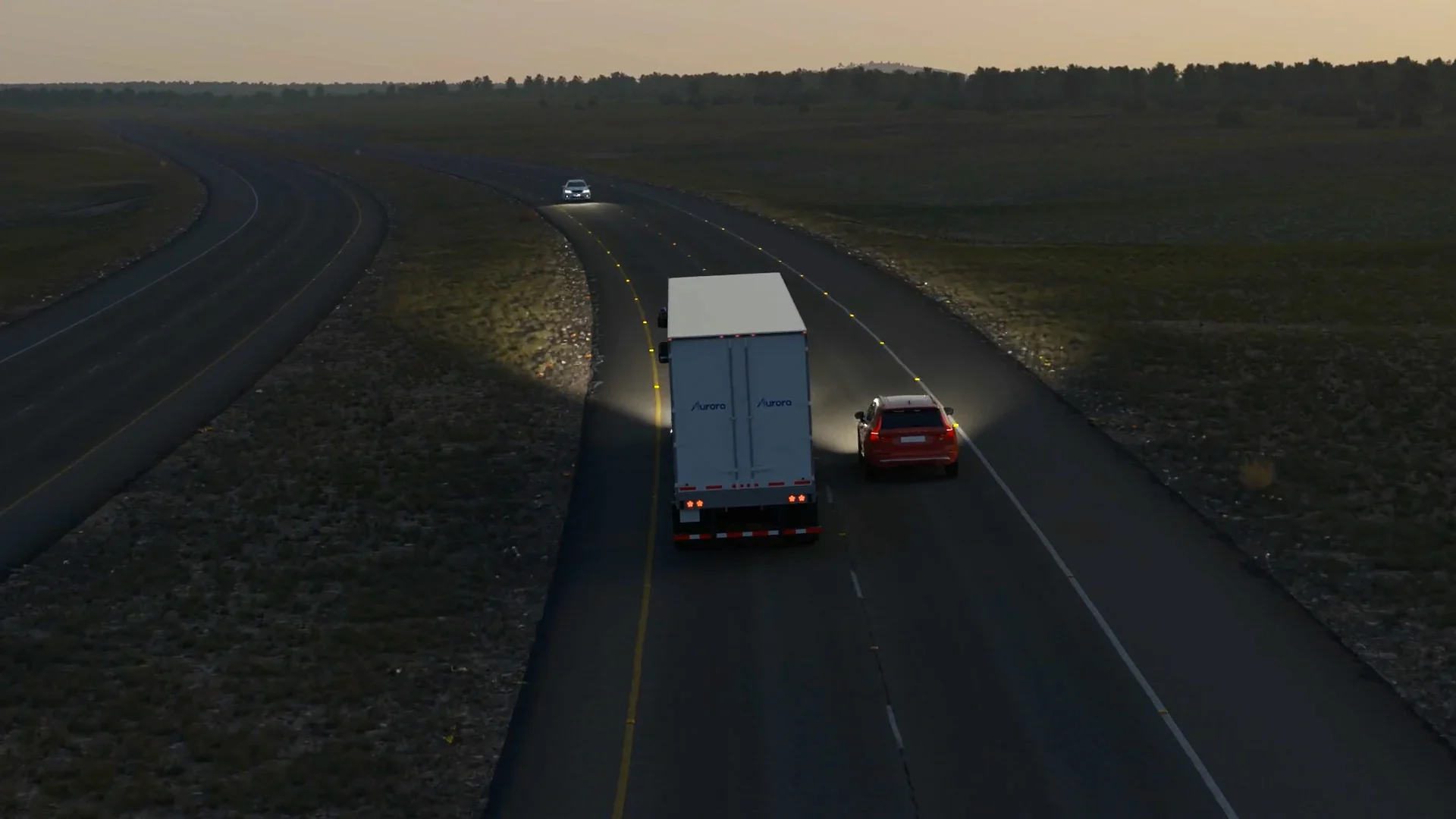 Back of an Aurora truck driving at dusk with headlights on