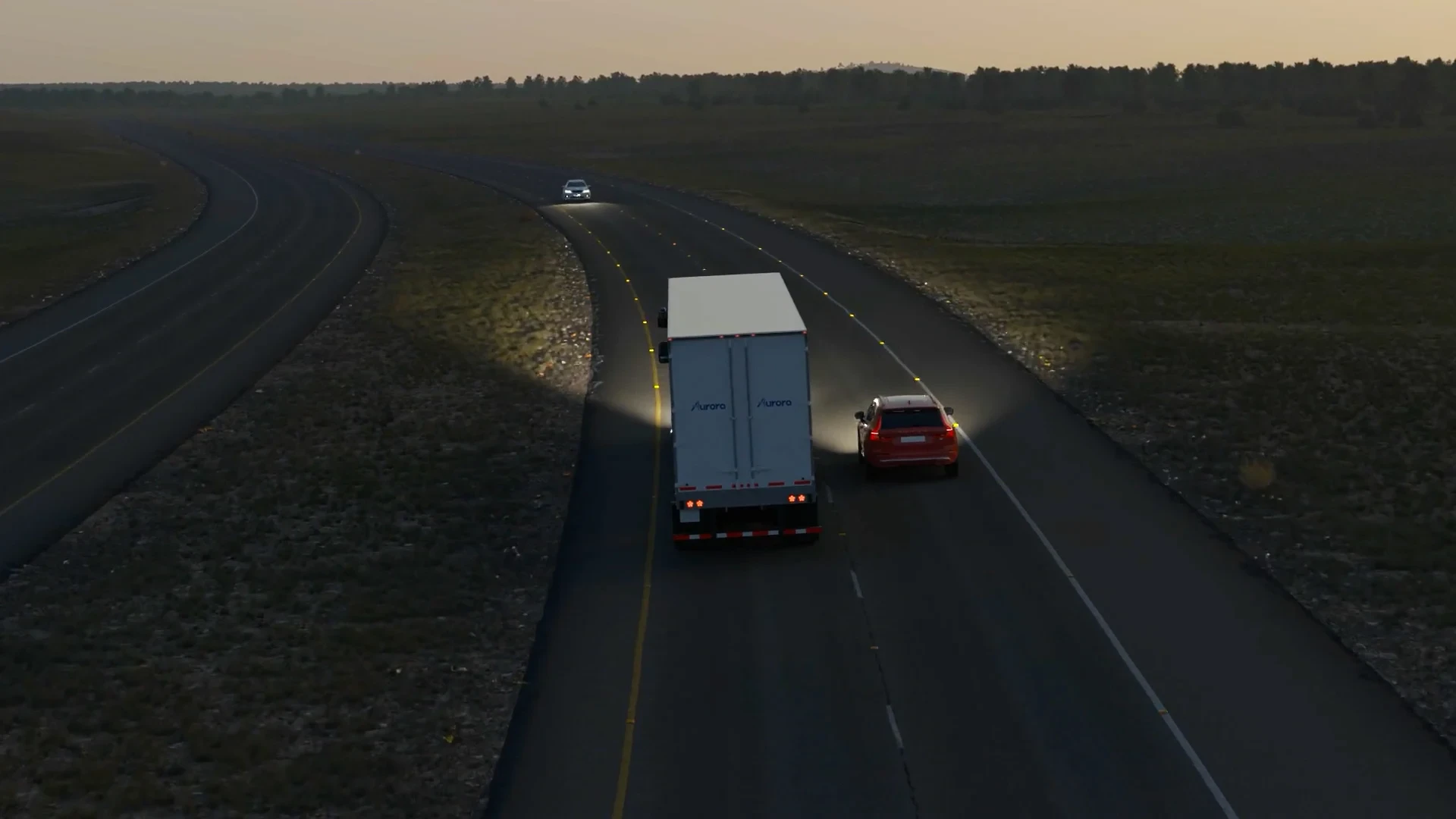 Back of an Aurora truck driving at dusk with headlights on