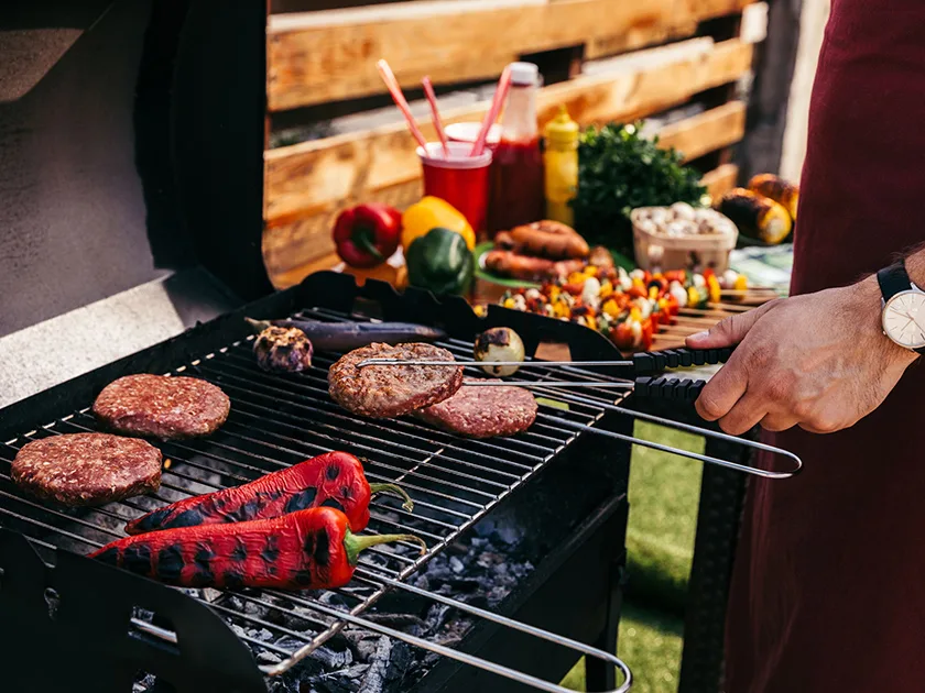 Mies grillaa kasviksia ja pihvejä