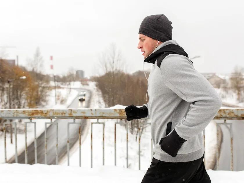 Mies juoksee talvisessa maisemassa