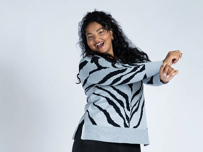 Iloinen nainen sinisessä seeprakuvioisessa neuleessa