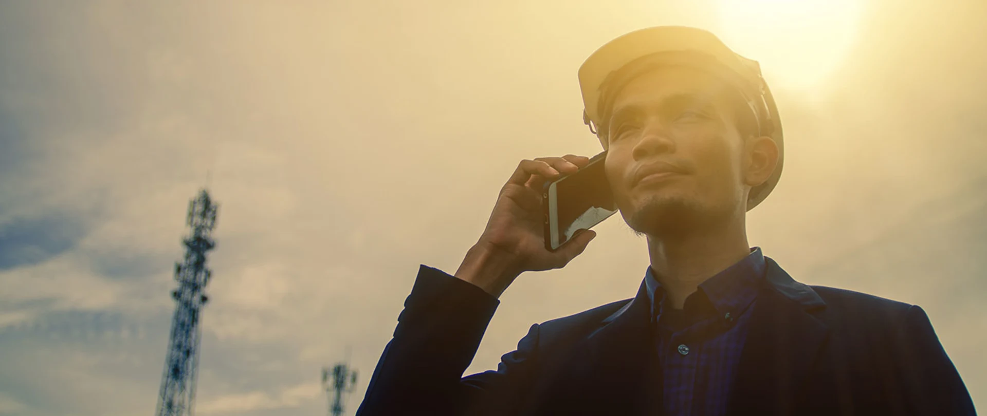 Man next to a telecommunications tower talking on his phone